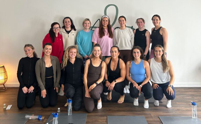 Group of women smiling on yoga mats.