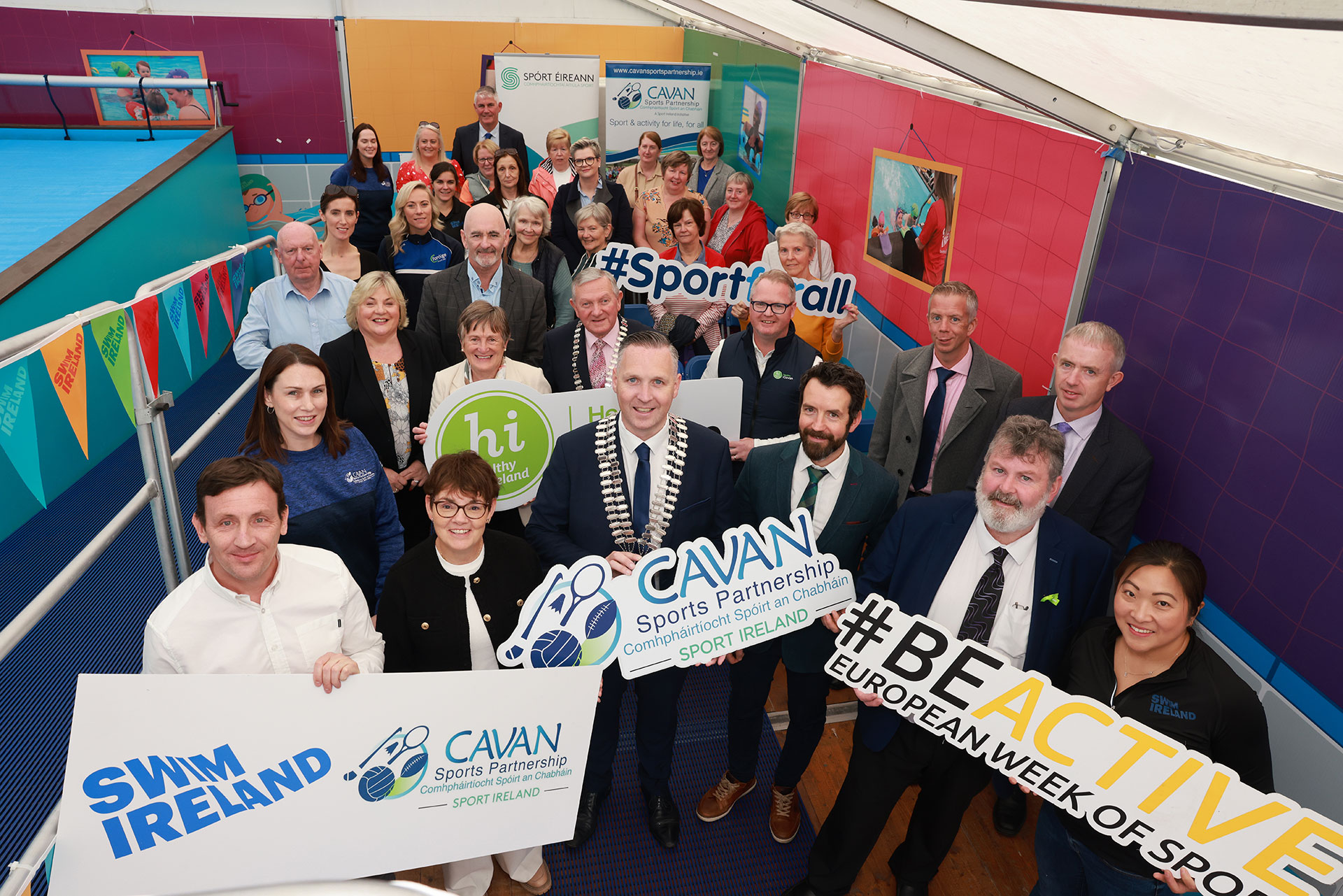 Group of people near swimming pool holding signs for Cavan Sports Partnership.