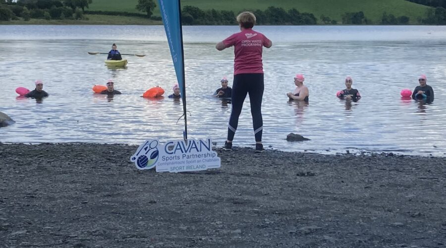 Woman teaching group in water while standing at shoreline.