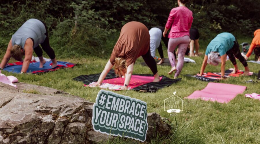Women do yoga on grass outdoors.